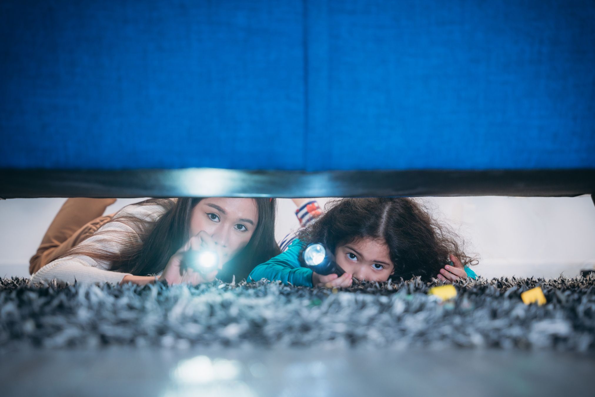 Mother and daughter looking under bed